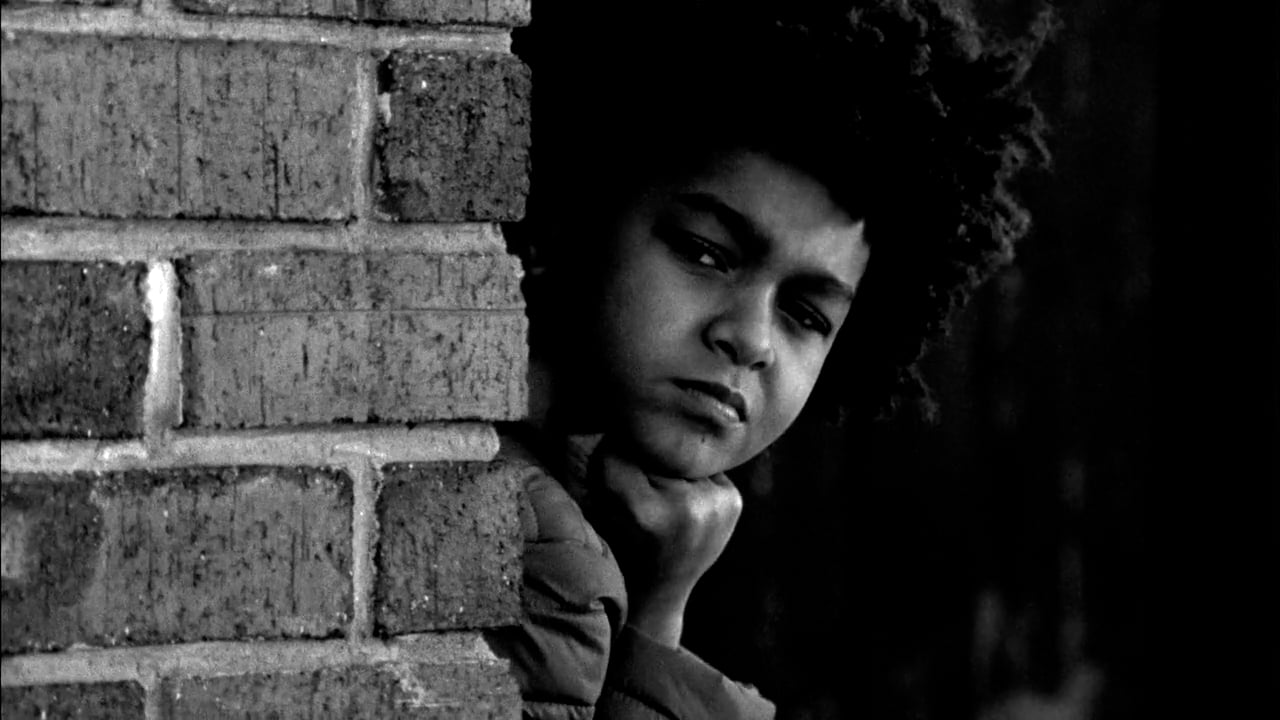 Streetplay — a boy watches from behind a brick wall